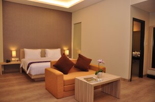 Una camera d'albergo con un letto, un divano, un comodino e un tavolino con una rivista.