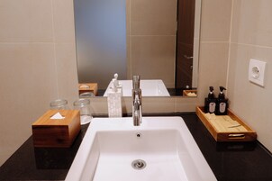 A bathroom with a white sink, a mirror, and toiletries on the counter.