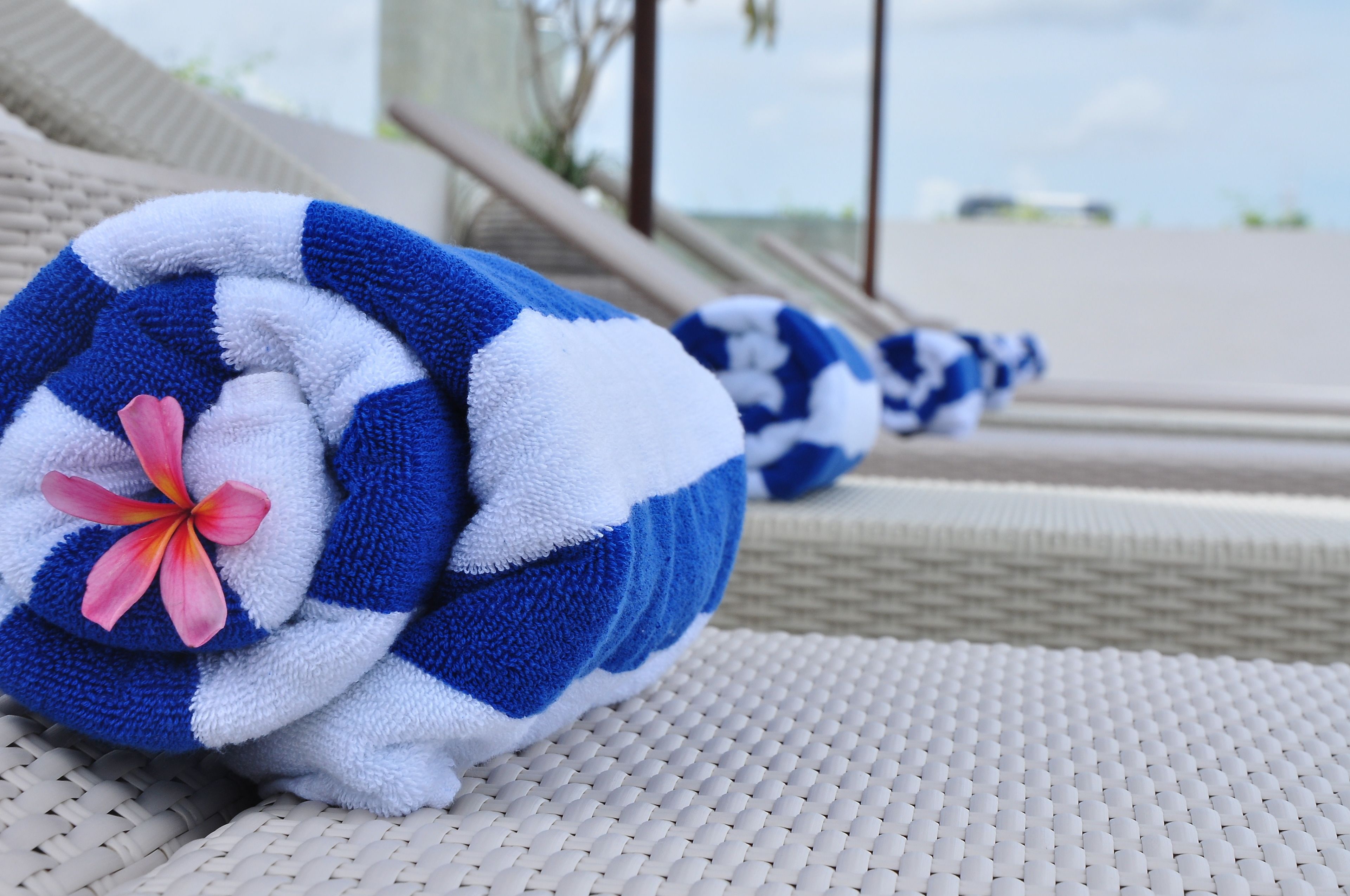 A towel with a flower, placed on a textured surface, likely in a hotel setting.