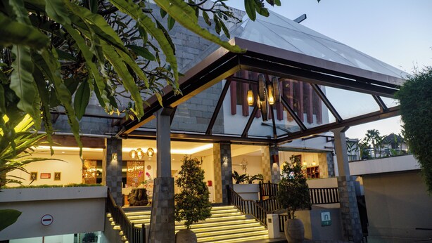 A modern hotel entrance with a covered outdoor area, a staircase, and a reception desk. - The Evitel Resort Ubud (Ubud)