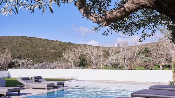 A pool area with lounge chairs and a view of a hillside. - Aelia Apartments (Andros)