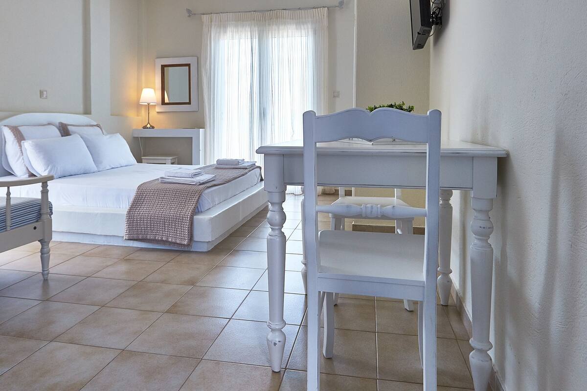A bedroom with a bed, bedside table, lamp, and a chair.