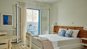 A bedroom with a bed, bedside table, and a window with curtains. - Aelia Apartments (Andros)