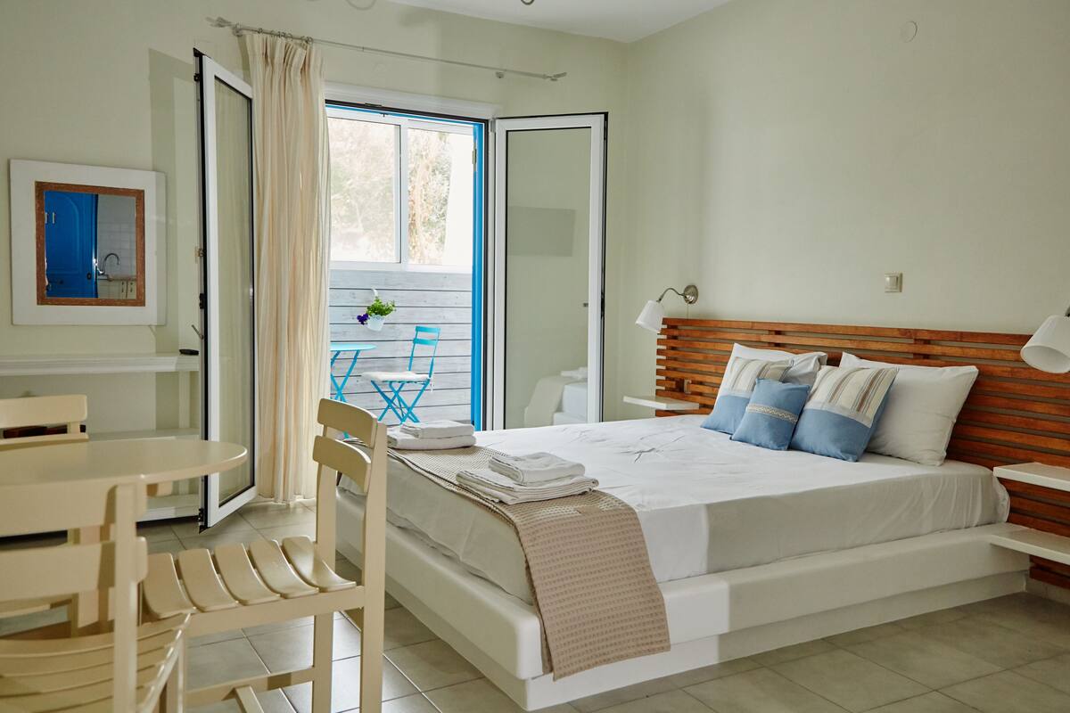 A bedroom with a bed, bedside table, and a window with curtains.