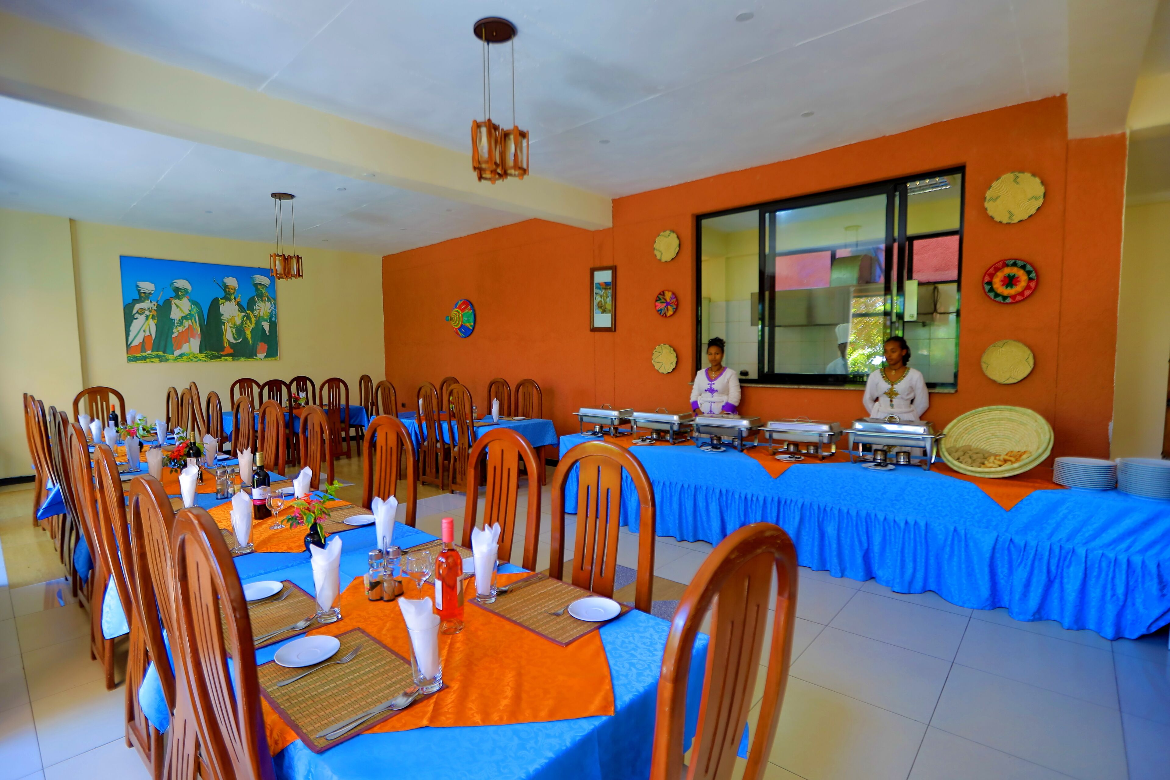 A dining area with tables set for a meal, chairs, and a buffet line.