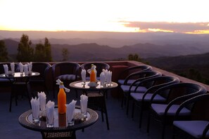Outdoor dining tables with chairs, arranged on a terrace with a view of distant mountains. - Harbe Hotel (Lalibela)
