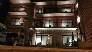 Un hotel de varios pisos con balcones, ventanas amplias y una entrada bien iluminada.