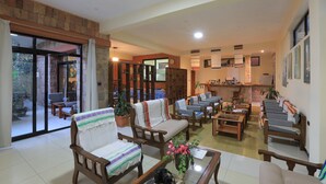 Un salón amplio con diversas opciones de asientos, chimenea y vistas a un patio exterior a través de grandes puertas de cristal.
