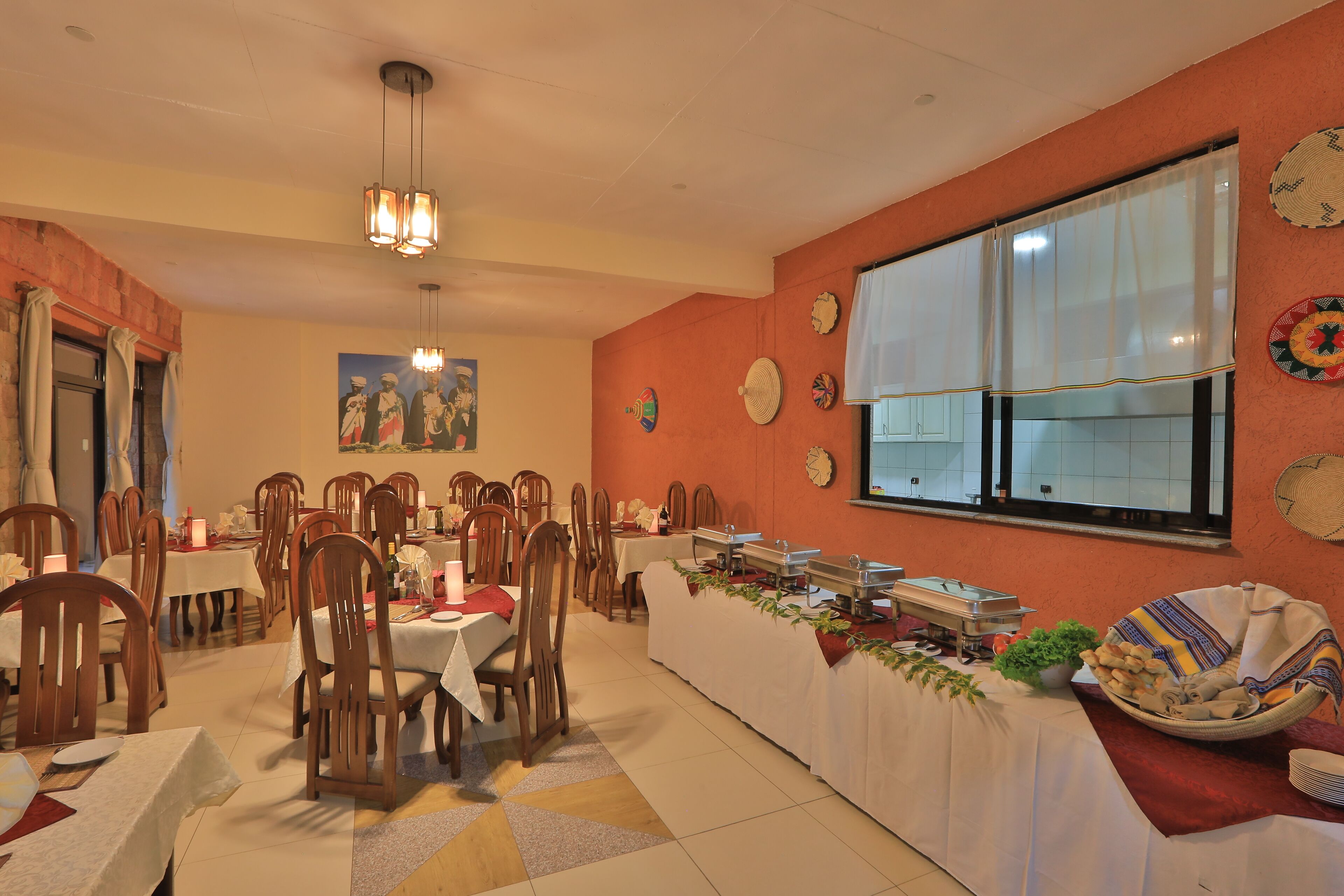 A dining area with multiple tables and chairs, a buffet setup, and decorative wall elements.