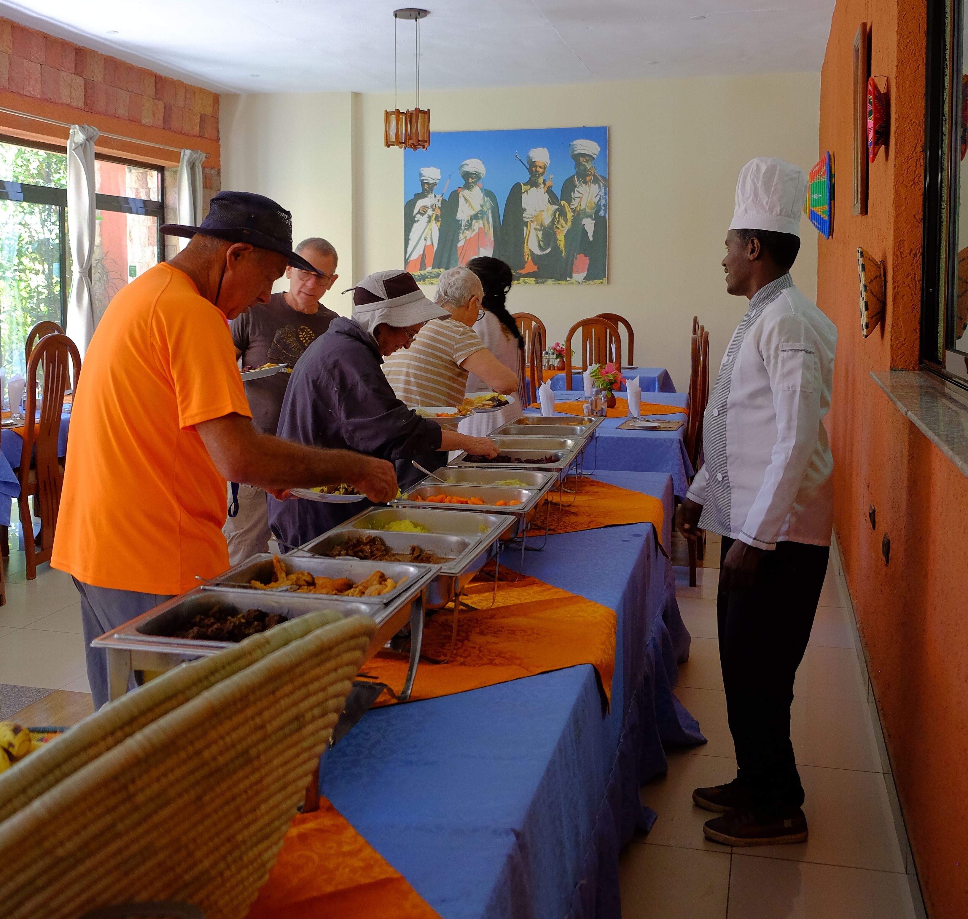 A buffet setup with multiple food stations and a long table covered with a blue tablecloth.