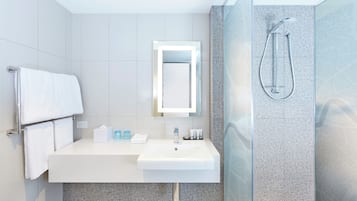 A modern bathroom with a white sink, mirror, and shower.