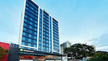 A modern hotel building with a Holiday Inn Express sign, large windows, and a clear sky.