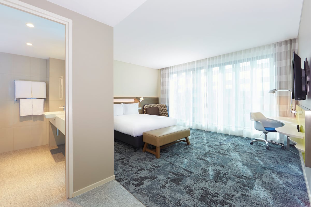 Une chambre d’hôtel équipée d’un lit, d’un bureau, d’une chaise, d’une télévision et d’une salle de bain avec un porte-serviettes.
