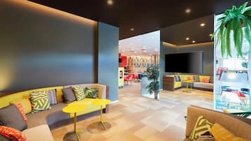 A modern living room with a sofa, yellow coffee table, and a flat-screen TV mounted on the wall.