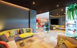 A modern living room with a sofa, yellow coffee table, and a flat-screen TV mounted on the wall. - Holiday Inn Express Brisbane Central by IHG (Spring Hill)