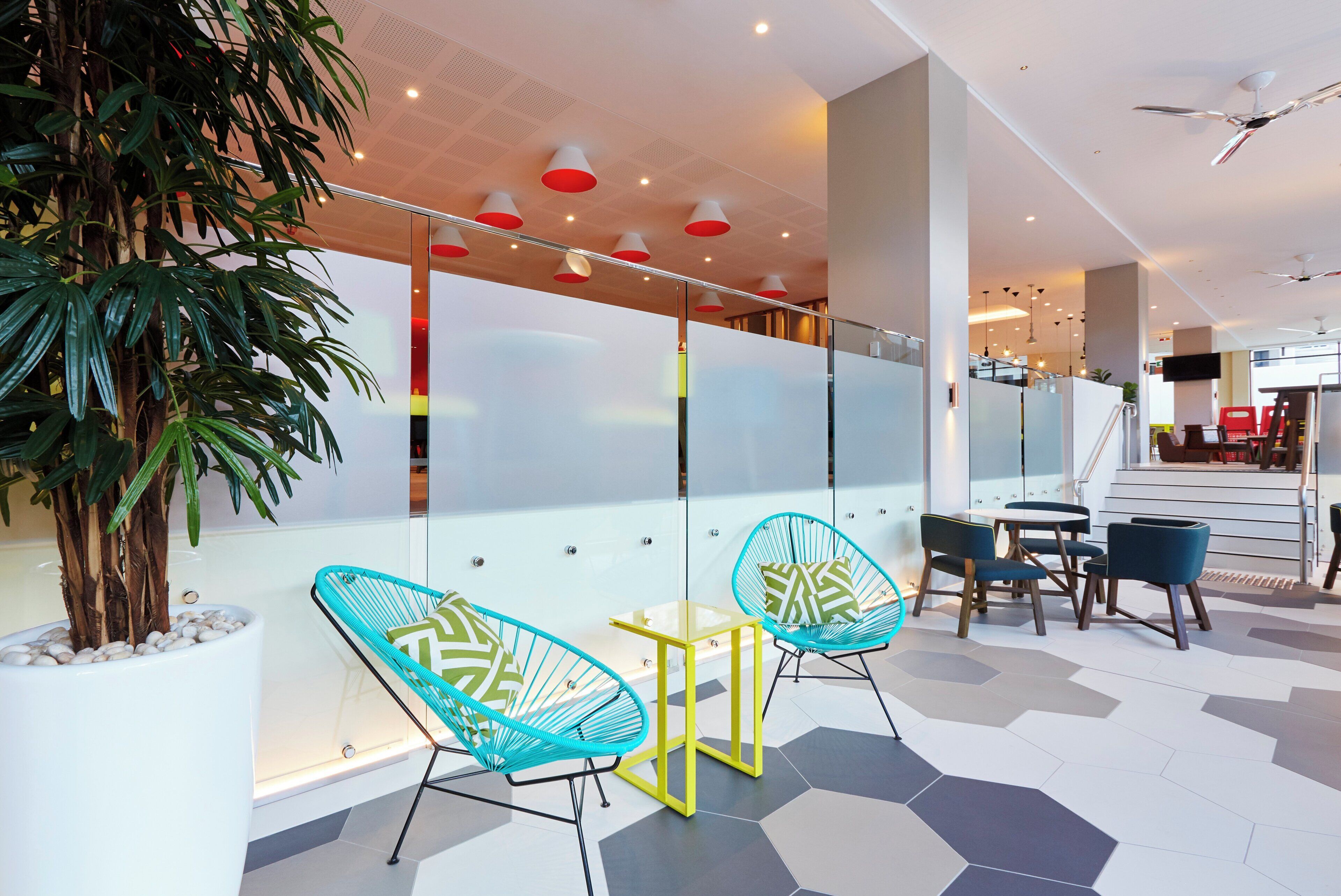 A modern indoor space with seating, a staircase, and a plant.
