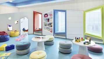 Children can play and relax in this vibrant playroom with seating areas, artwork, and shelves filled with toys and books.