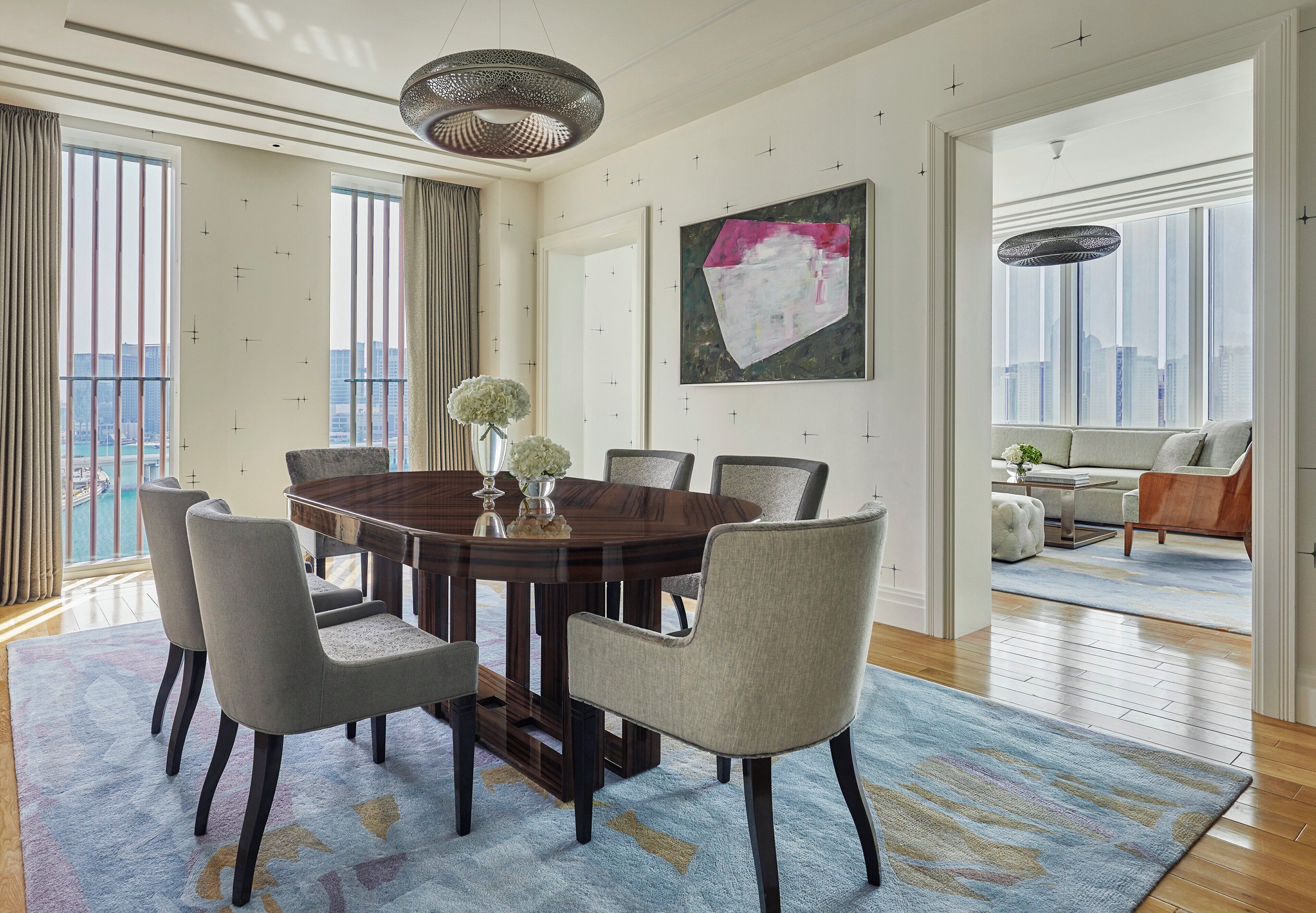 A dining area with a round table, six chairs, and a vase with flowers.
