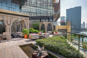 A rooftop terrace with outdoor seating, a decorative star sculpture, and a view of the city skyline.