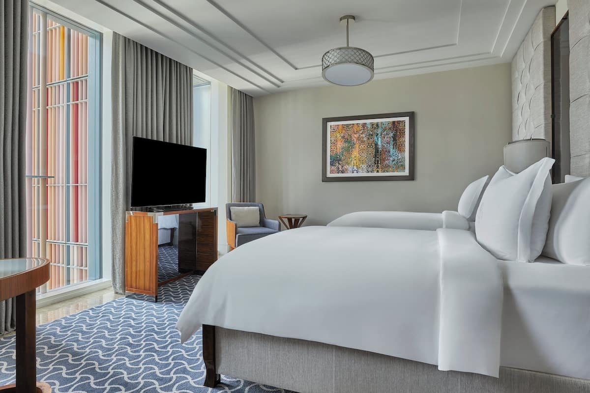 Ein modernes Hotelzimmer mit einem großen Bett, einem Flachbildfernseher, einem Schreibtisch und einem Sessel.