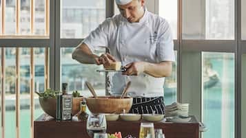 A chef preparing food in a modern kitchen with large windows overlooking a cityscape.
