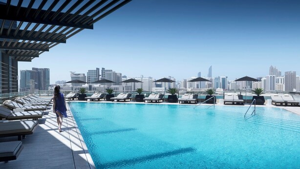 A rooftop pool with lounge chairs and umbrellas, overlooking a city skyline. - Four Seasons Hotel Abu Dhabi at Al Maryah Island (Abu Dhabi)