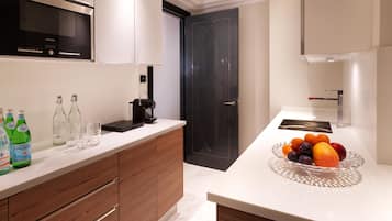 A modern kitchen with wooden cabinets, a black door, and a fruit bowl on the counter.
