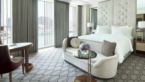 A hotel room with a large bed, a sofa, a small table with a vase, and a view of the city. - Four Seasons Hotel Abu Dhabi at Al Maryah Island (Abu Dhabi)