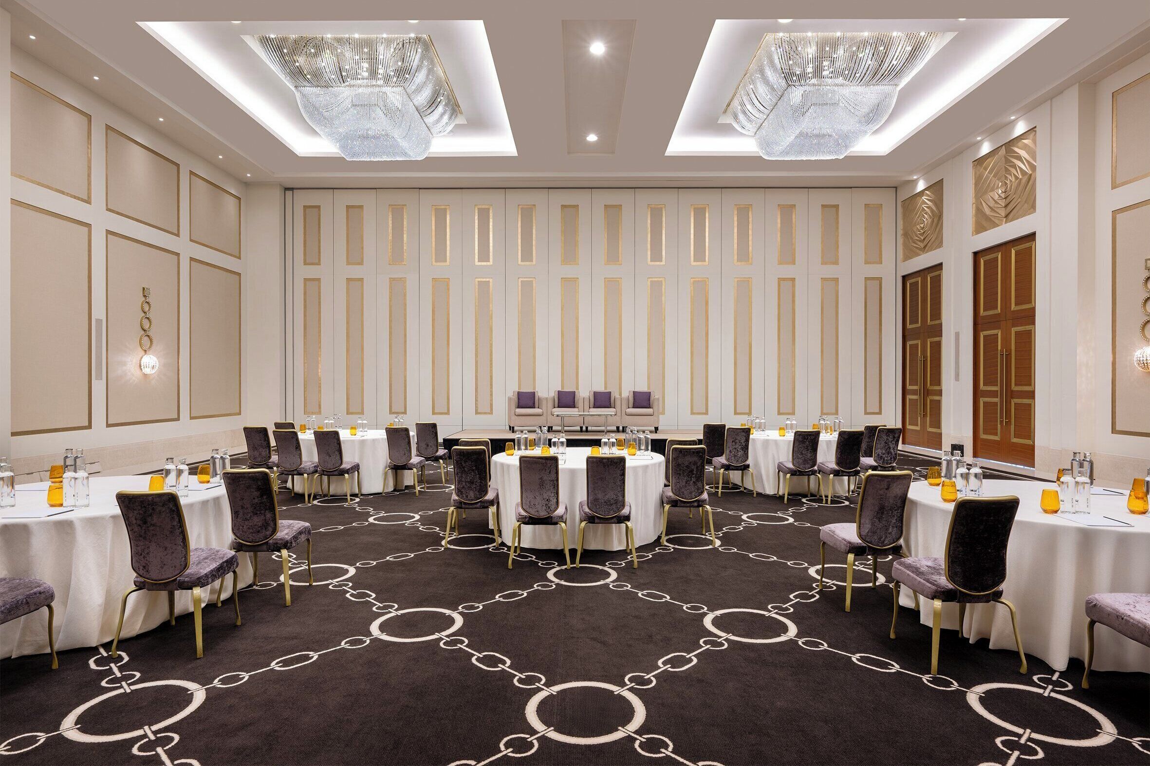 A conference room with round tables, chairs, and a carpeted floor.