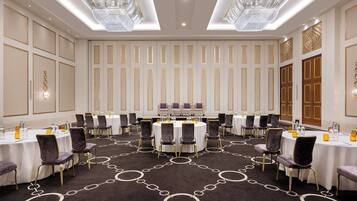 A conference room with round tables, chairs, and a carpeted floor.
