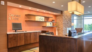 A reception desk with a "Connect & Print" sign, a computer monitor, and a printer. There are shelves with decorative items and a stone accent wall. - Fairfield Inn & Suites by Marriott Philadelphia Horsham (Willow Grove)
