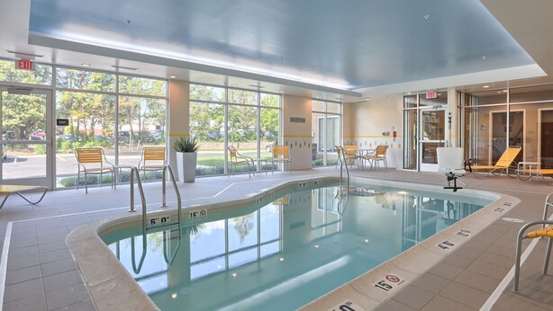 An indoor swimming pool with clear markings, sunlit interior, and outdoor seating area visible through large windows. - Fairfield Inn & Suites by Marriott Philadelphia Horsham (Willow Grove)