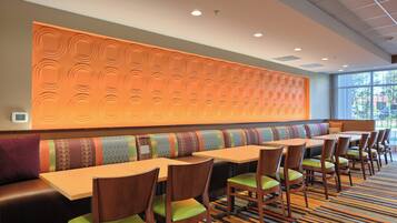 A restaurant with a long counter, multiple booths, and a patterned wall.