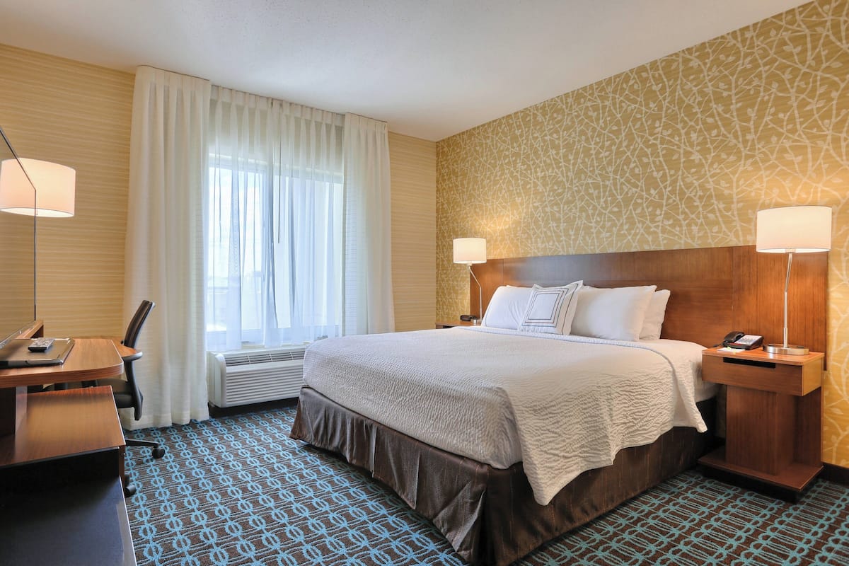 A hotel room with a large bed, two bedside tables, a desk, and a chair.