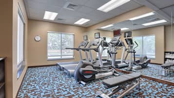 A gym with treadmills, elliptical machines, and weight benches.