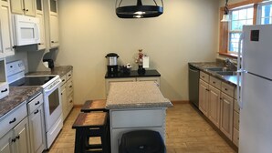 A kitchen with white cabinets, a black countertop, a stove, a sink, and a window.