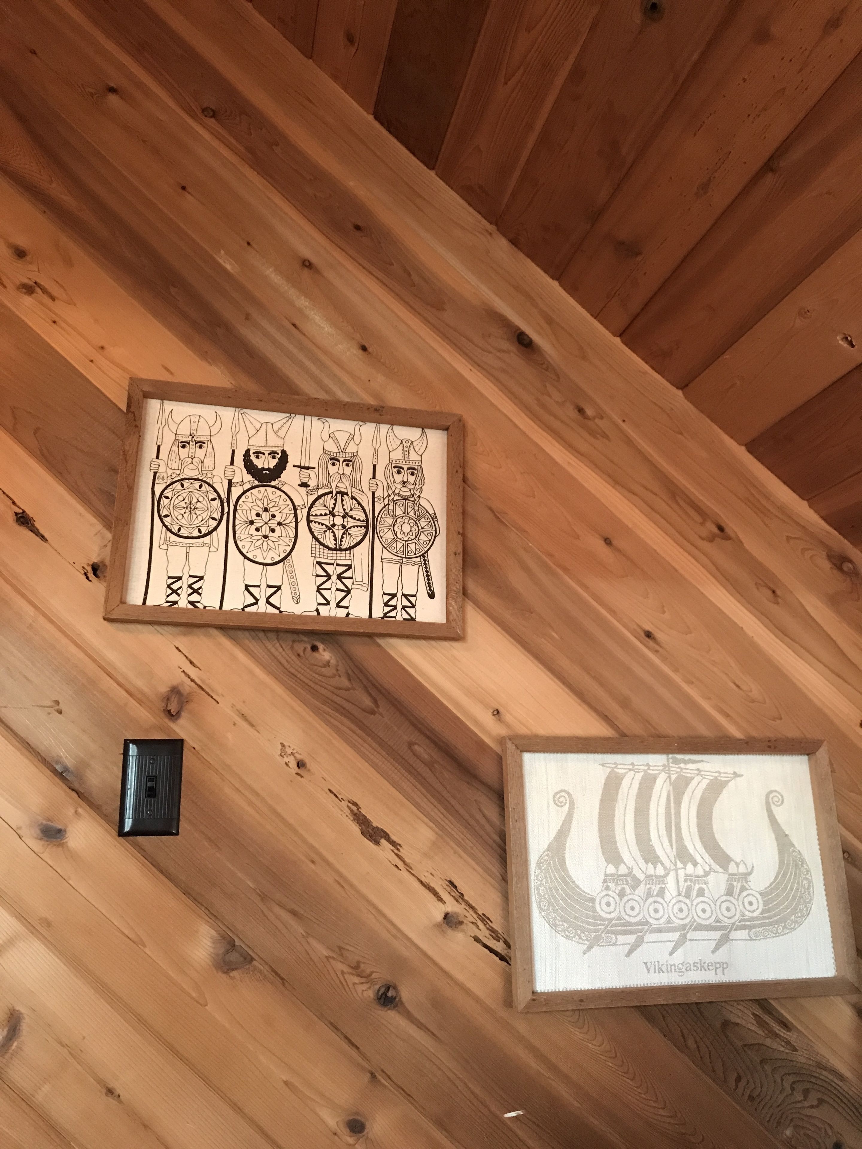 Et træloft med et indrammet vikingamotiv og et indrammet design af et vikingeskib.