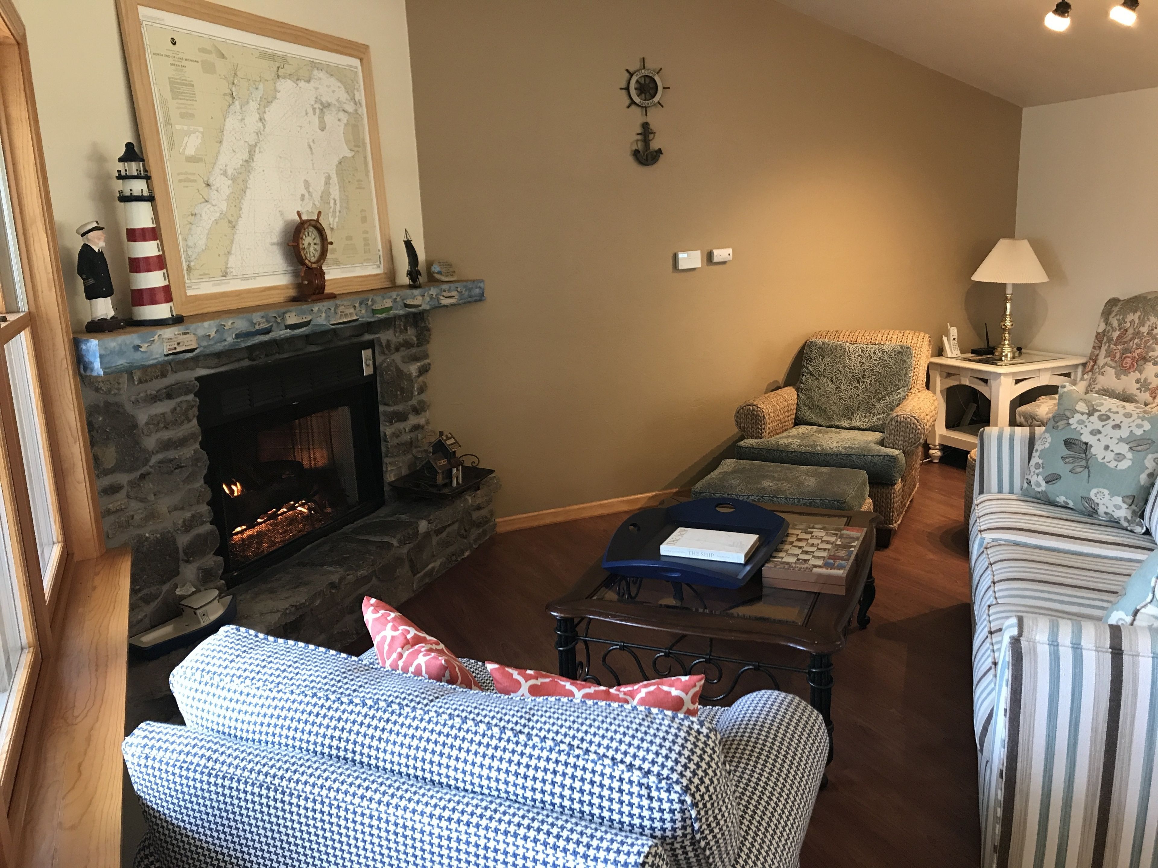 Un salon chaleureux avec une cheminée en pierre, une carte accrochée au mur et un coin salon confortable avec un canapé et des fauteuils.
