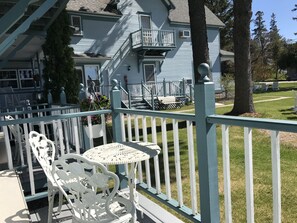 A blue house with a white porch, white railing, and a small table with chairs.