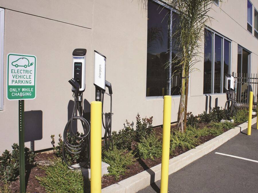 Una estación de carga para vehículos eléctricos con un letrero que indica que es solo para estacionamiento de vehículos eléctricos durante la carga.