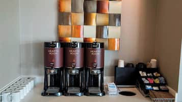 Three coffee machines labeled "HEARTH ROOM" on a counter with disposable cups and a tray of utensils.