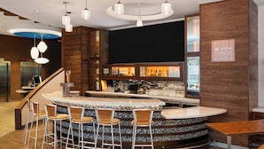 Een moderne bar met een gebogen toonbank, barstoelen en een houten accentmuur.