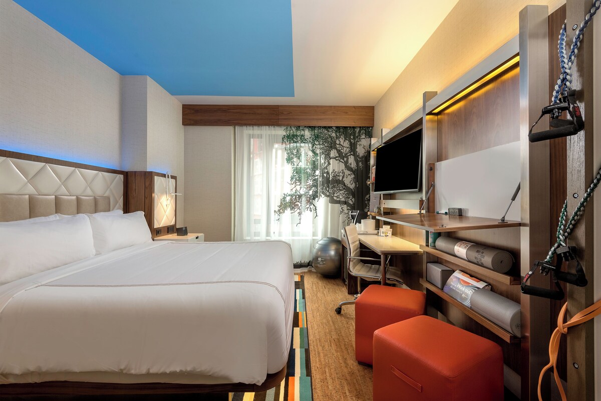 Een hotelkamer met een groot bed, een bureau, een televisie en een zithoek.