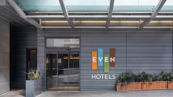 A hotel entrance with a modern design, featuring a glass door and a sign that reads 'EVEN HOTELS.'