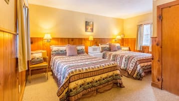 A room with two beds, wooden walls, a ceiling with a grid pattern, and a single window with curtains.