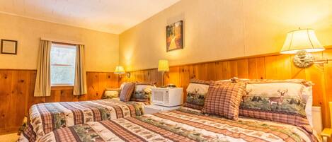 A cozy bedroom with two beds, wooden paneling, a window with curtains, and wall-mounted lamps.