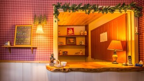 Un área de bar acogedora con un mostrador de madera, un menú en una pizarra que enumera aperitivos y bebidas, y un letrero que indica 'PURE MARBLE PRODUCTS SOLD HERE'.
