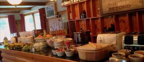 A bar area with shelves of liquor bottles, a sign reading "With Soul Beyond", and a buffet setup with various dishes and containers.