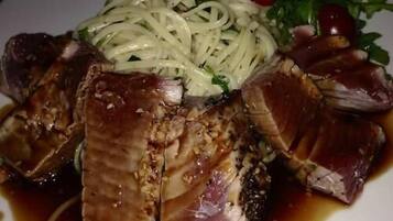 Un plato de comida con carne en rodajas, fideos y verduras.