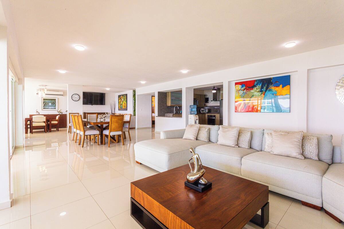 A modern living room with a sofa, coffee table, and dining area.